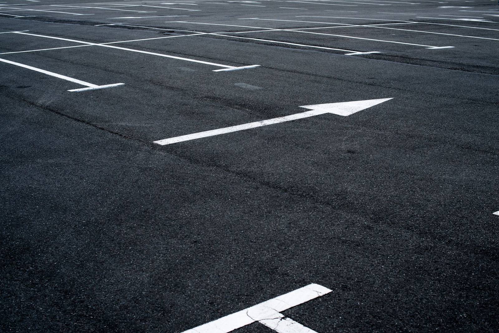 Freshly paved asphalt lot with new white directional striping
