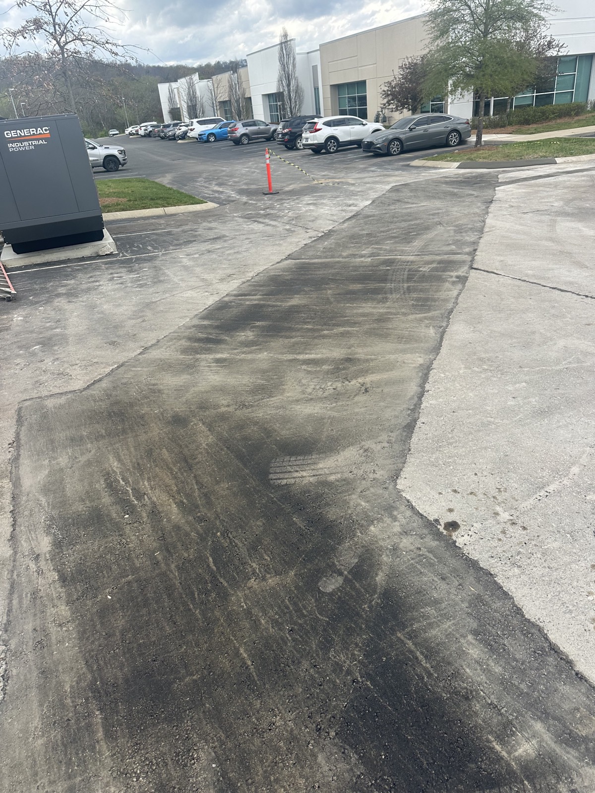 A failed section of a commercial drive aisle cut out and milled down to a clean edge, ready for new asphalt, at an office park