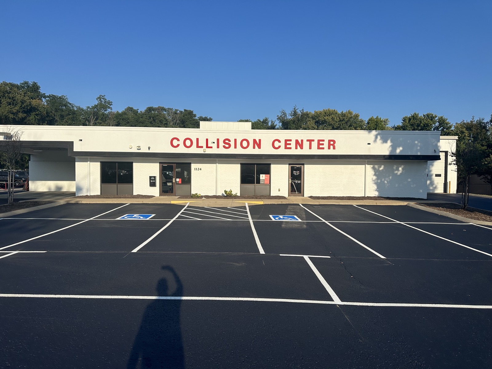 Freshly sealcoated and restriped commercial stalls, including two accessible spaces with a hatched access aisle